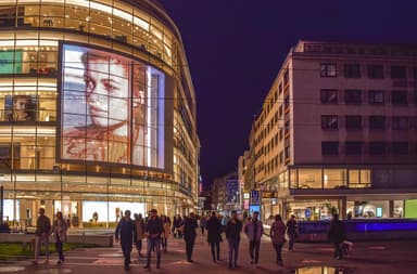 Evening shoppers outside lit storefronts on a European retail street, the consumer backdrop to the Klarna shareholder investigation