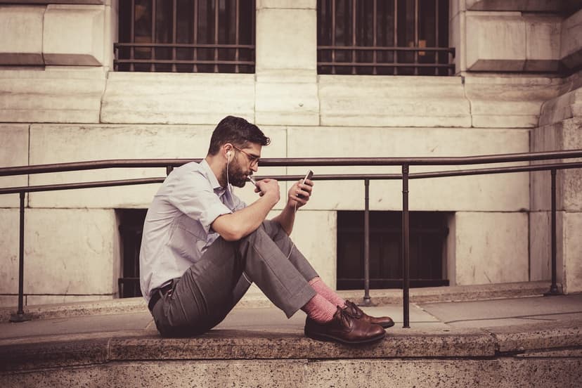 Man sitting on steps using his smartphone, illustrating Moov Money person-to-person payments to a debit card