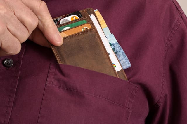 Shopper taking a payment card from a wallet, illustrating SoFiUSD card settlement on Mastercard