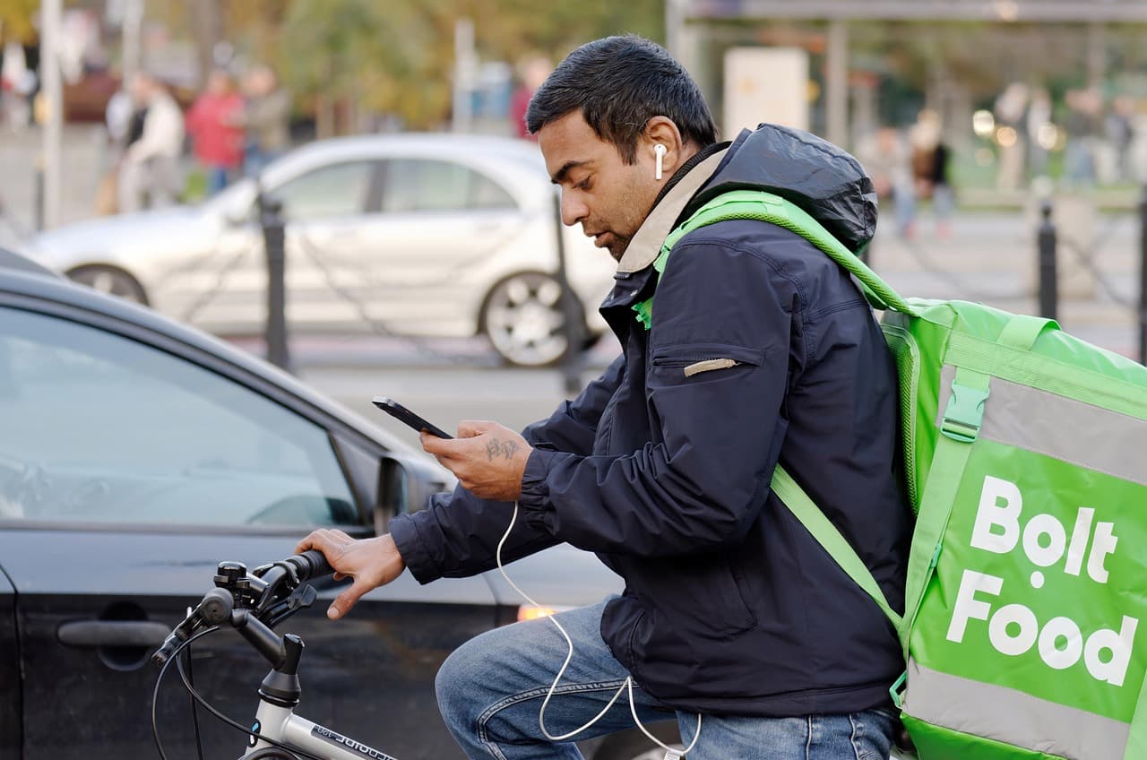 Ualett Global Transfer, gig economy delivery courier checking a phone